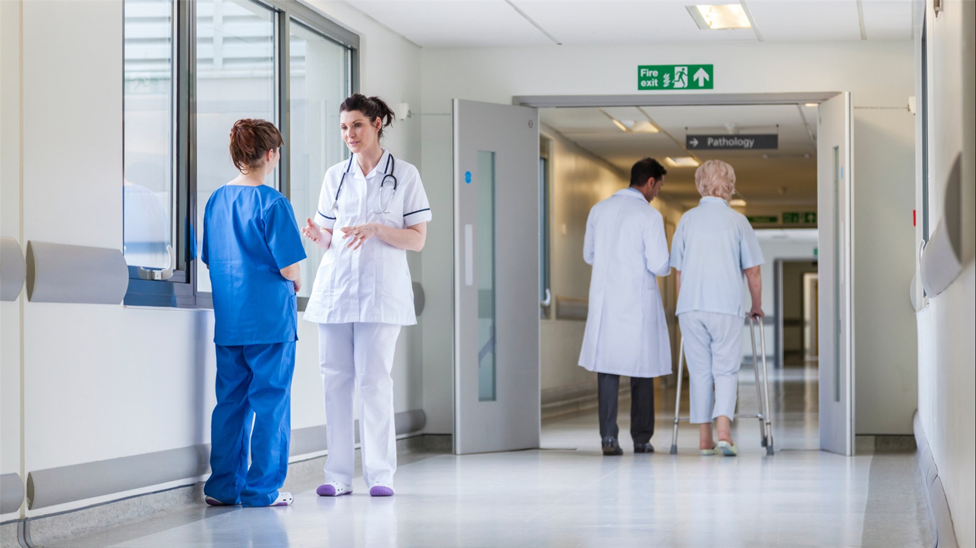 zwei Menschen in Krankhauskleidung unterhalten sich auf einem Krankenhausflur